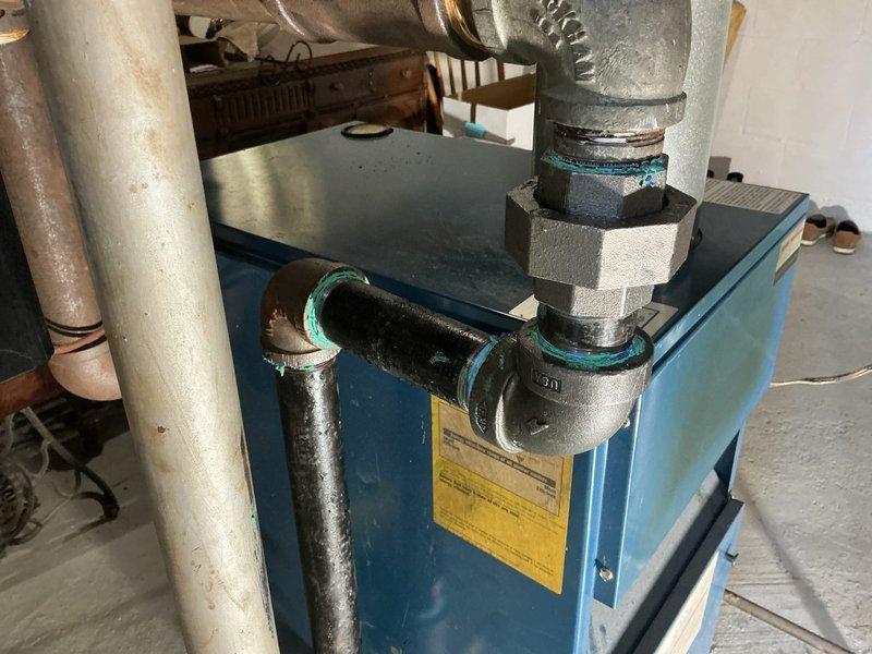# Boiler System Repair and Component Replacement

Responded to service call for boiler system requiring repairs. Upon inspection, identified aging plumbing connections with visible corrosion and deterioration on copper and brass fittings, particularly noting green patina formation indicating oxidation on metal components.

Performed comprehensive repairs to the blue-cased boiler unit's piping system. Replaced deteriorated pipe sections and installed new turquoise-colored rubber couplings to ensure proper sealing and prevent future leaks. Addressed corroded vertical pipes running along the left side of the unit that showed significant wear and surface weathering.

Installed new gas shutoff valve assembly with yellow handle for improved safety and accessibility. Connected valve to gray metal pipes using turquoise compression fittings to ensure secure, leak-free connections. Replaced aging black plastic pipe sections that exhibited brown discoloration and signs of degradation.

Inspected 