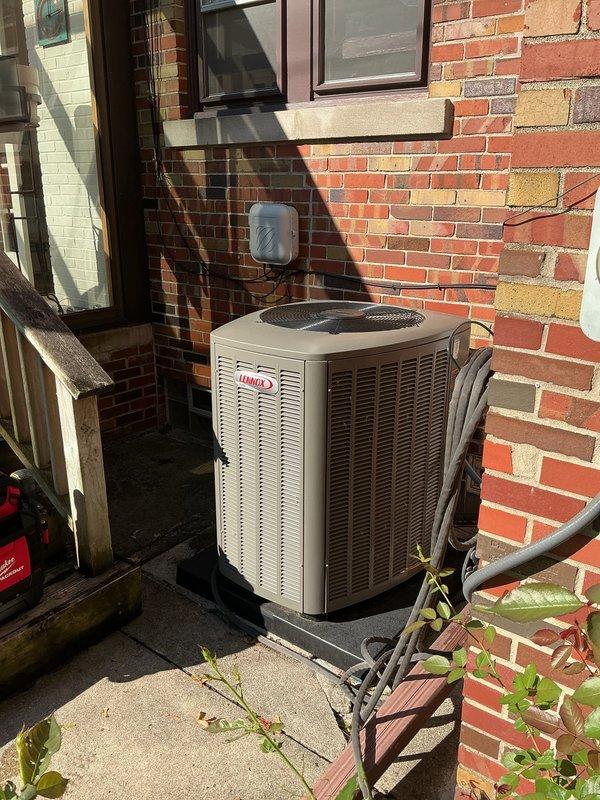 Responded to service call for recently installed one-year-old Lennox air conditioning system experiencing partial cooling issues affecting entire home. Upon arrival, discovered water accumulation in overflow drain pan and red indicator light on system sensor, suggesting drainage blockage or float switch activation. Inspected indoor air handler unit located in attic storage area and outdoor condenser unit positioned on concrete pad against brick exterior wall. Diagnosed condensate drain line obstruction preventing proper water evacuation from system. Cleared blockage from condensate drain line, verified proper drainage flow, and reset safety sensor. Tested system operation to confirm full cooling capacity restored and proper airflow throughout home. Overflow pan now draining correctly with no water accumulation. All safety indicators functioning normally with no warning lights present. System operating within manufacturer specifications.