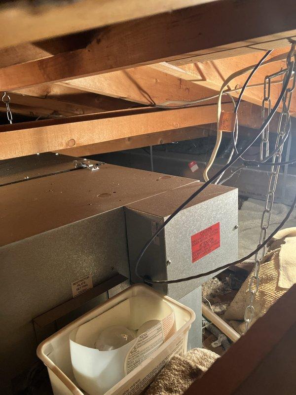 Conducted on-site evaluation of a 20-year-old residential air conditioning system that was blowing air but not cooling. Inspected outdoor condenser unit positioned on concrete pad against brick exterior and assessed attic-mounted air handler equipment. Documented existing system configuration and provided replacement estimate for complete HVAC system due to age and non-cooling condition.