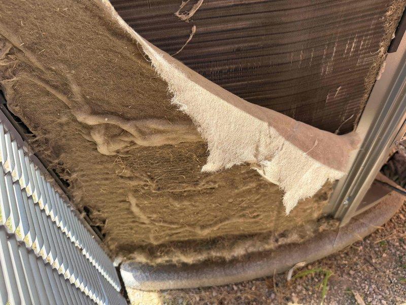 Responded to service call for 2-year-old air conditioning system experiencing delayed startup and unusual noises during operation. Upon inspection, discovered outdoor condenser unit with severe accumulation of dirt, debris, and organic matter coating the condenser coils and top surfaces, significantly restricting airflow and heat transfer capability. Performed thorough cleaning of condenser coils and exterior surfaces to remove heavy buildup. Verified thermostat operation and system response. Unit now operating normally with proper startup timing and reduced noise levels.