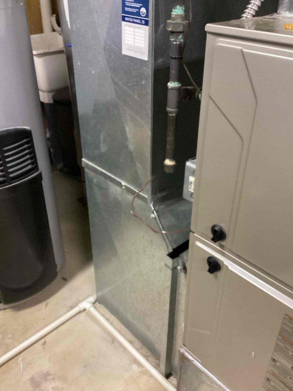 Responded to service call for air conditioning system not cooling properly with thermostat indicating temperature rising during cooling cycle. Upon inspection, discovered water leakage and ice buildup on refrigerant line exiting to outdoor unit, indicating potential evaporator coil freeze-up due to restricted airflow or low refrigerant charge. Documented existing Bryant HVAC system configuration in basement mechanical room and provided comprehensive estimate for complete system replacement, including discussion of possible zoned system installation to address cooling distribution concerns.