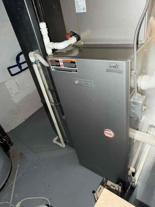 Responded to service call for water leaking from furnace during air conditioning operation at basement-located Payne air handler unit of undetermined age. Upon inspection, identified condensate drainage issue causing water accumulation. Addressed problematic condensate drain line configuration where PVC drainage pipes were improperly installed or blocked, preventing proper water evacuation from the evaporator coil. Cleared obstruction, verified proper drainage flow, and ensured condensate line was functioning correctly to eliminate water leakage issue.