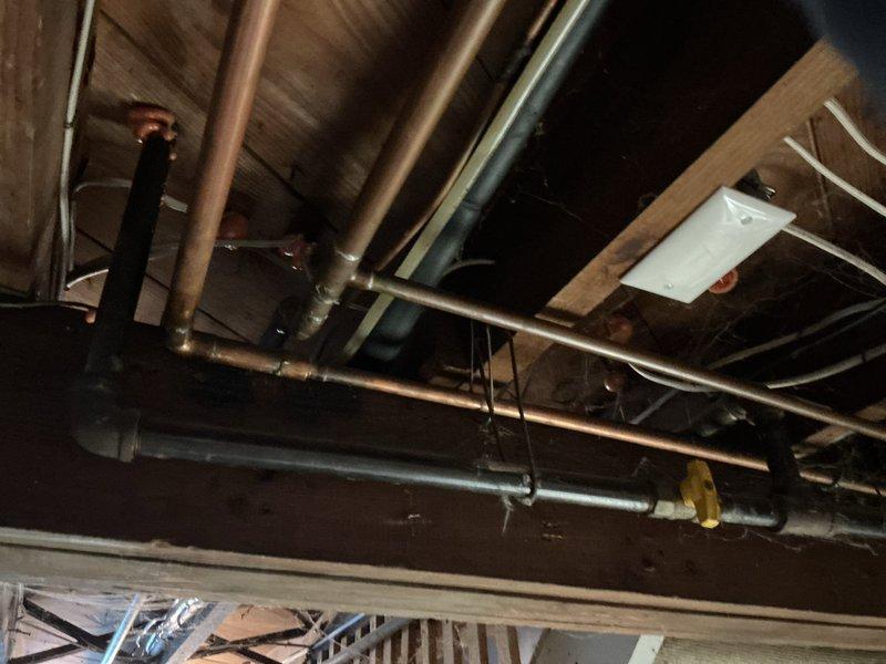 Responded to service call to cap gas line in preparation for new stove installation. Electrician on-site required gas line to be properly capped before proceeding with their electrical work. Located existing gas supply line in basement/crawlspace area running through floor joists. Verified gas supply was shut off at main valve with yellow handle. Successfully capped the gas line stub-out using appropriate brass cap fitting, ensuring secure threaded connection. Pressure tested the capped line to confirm no leaks. Work completed to allow electrical contractor to proceed safely with stove circuit installation.