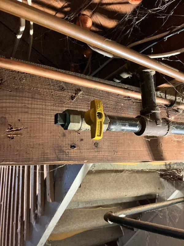 Responded to service call to cap gas line in preparation for new stove installation. Electrician on-site required gas line to be properly capped before proceeding with their electrical work. Located existing gas supply line in basement/crawlspace area running through floor joists. Verified gas supply was shut off at main valve with yellow handle. Successfully capped the gas line stub-out using appropriate brass cap fitting, ensuring secure threaded connection. Pressure tested the capped line to confirm no leaks. Work completed to allow electrical contractor to proceed safely with stove circuit installation.