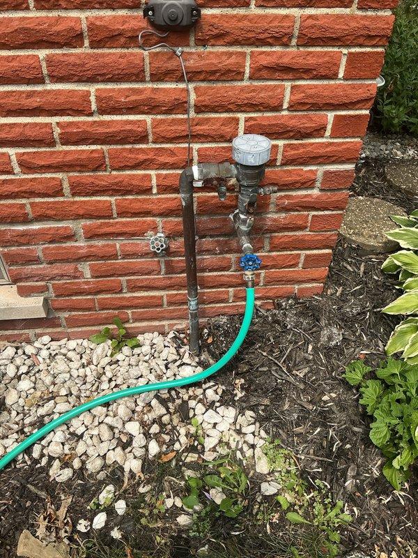 Installed PVB (Pressure Vacuum Breaker) backflow preventer for residential sprinkler system per estimate. The assembly was mounted on exterior brick wall with proper shut-off valves and connection points for garden hose attachment. Interior piping connections were completed in attic space, routing copper supply lines and securing all components to structural beams with appropriate brackets and fasteners to ensure code-compliant backflow prevention for the irrigation system.