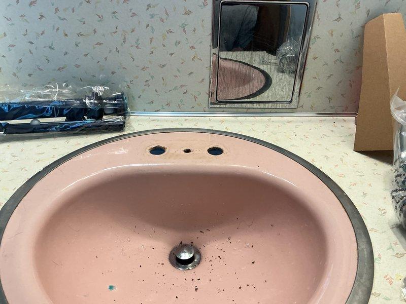Installed new chrome two-handle faucet assembly on existing pink oval bathroom sink per customer estimate. Completed mounting of faucet with hot and cold water handles and central spout, ensuring proper connections and testing for leaks. All fixtures are operational and ready for use.