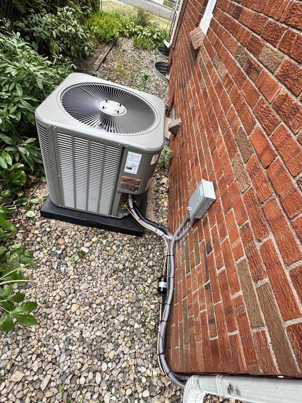 Completed full installation of 2.5-ton air conditioning system with new evaporator coil in right side yard location. Unit positioned on gravel pad against brick exterior wall with electrical disconnect box mounted above, refrigerant lines properly insulated and routed through wall, and all electrical conduit secured per code requirements. System reconnected, tested, and left operational with all mechanical, electrical, and air conditioning permits requested and processed.