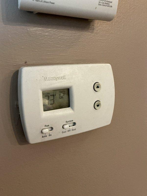 Responded to no cooling complaint on 8-year-old residential air conditioning system located in basement. Performed comprehensive leak search on refrigerant circuit and identified active refrigerant leak causing loss of cooling capacity. Conducted system evaluation and documented equipment condition with thermostat reading 73°F ambient with setpoint at 62°F, confirming inadequate cooling performance.