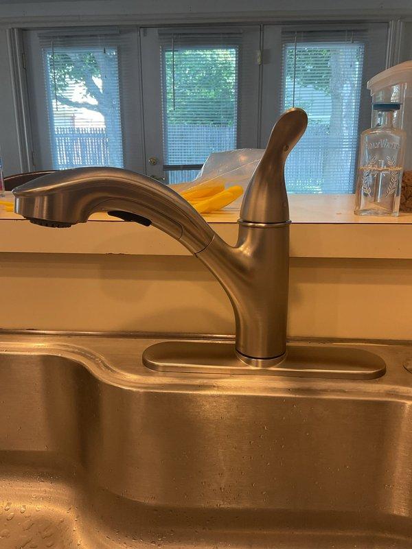 Completed installation of new kitchen sink faucet and garbage disposal unit. Replaced existing fixtures with modern single-handle faucet in brushed nickel finish, mounted on deck plate over stainless steel double-bowl sink configuration. Installed black garbage disposal unit with proper mounting hardware and electrical connection. Connected white PVC drainage system with P-trap configuration to wall drain, ensuring proper slope and secure fittings. Tested all connections for leaks, verified disposal operation, and confirmed water flow through faucet and drainage system functioning properly.