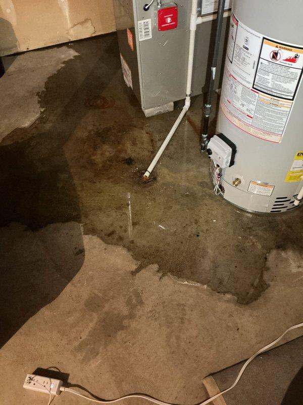 Responded to water leak concern in basement utility area where excessive water had been appearing near furnace and recently installed water heater for 4-5 days. Upon inspection, found extensive water staining and pooling on concrete floor throughout mechanical room. Investigated both the new water heater installed on 11/7/25 and HVAC condensation system as potential sources. Documented conditions showing dark discoloration and moisture damage across floor surface, with water accumulation most prominent in center area between furnace unit and water heater. Examined all plumbing connections, drain lines, and condensate discharge points. Photographed wet conditions and equipment for documentation purposes. Determined source of water intrusion and provided recommendations for remediation in fifty-year-old home.