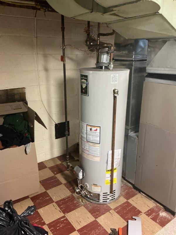Completed installation of new tanked water heater in basement utility room to replace failing unit that was not producing adequate hot water. Installed new white cylindrical tank water heater with proper copper and black pipe connections at top of unit, ensuring all plumbing connections were secure and code-compliant. Additionally, replaced shower cartridge in bathroom to address separate plumbing issue. Provided customer with information regarding maintenance program options and furnished comparative quotes for both tanked and tankless water heater systems for future reference.