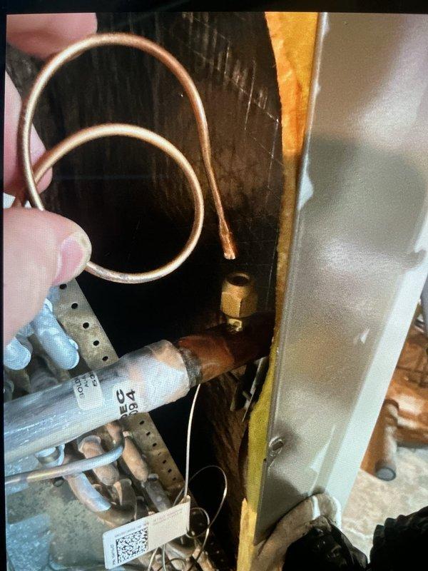 Completed comprehensive Gold AC inspection on one-year-old system with air handler located in basement. Identified failed TXV requiring replacement; part ordered from Lennox (PO# 1352510-001) with shipment to Madison Heights location. Inspected copper refrigerant lines, evaporator coil, and associated mechanical components; documented existing installation with photos showing coil assembly, copper tubing connections, filter drier, and ductwork configuration within confined utility space.