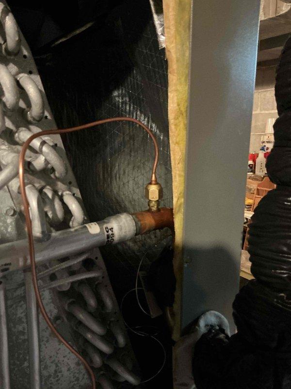 Completed comprehensive Gold AC inspection on one-year-old system with air handler located in basement. Identified failed TXV requiring replacement; part ordered from Lennox (PO# 1352510-001) with shipment to Madison Heights location. Inspected copper refrigerant lines, evaporator coil, and associated mechanical components; documented existing installation with photos showing coil assembly, copper tubing connections, filter drier, and ductwork configuration within confined utility space.