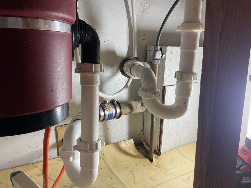 Successfully snaked the kitchen drain line to clear the blockage and restore proper drainage. Accessed the system through the P-trap assembly beneath the double-basin sink, navigating past the garbage disposal connection. Upon completion, verified water flow through both basins and confirmed the drain system was functioning properly with no leaks at the connections.