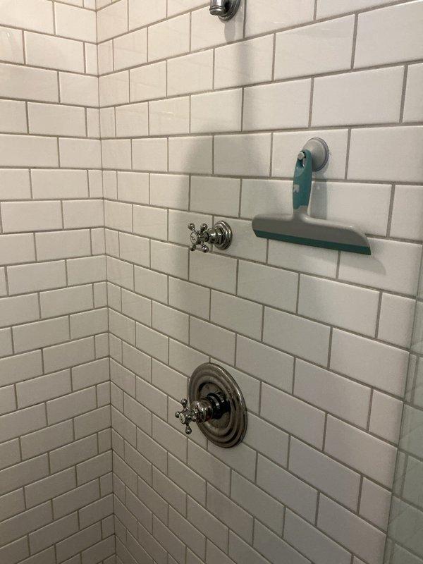 Responded to service call for malfunctioning shower fixtures including a dripping showerhead following previous repair and inoperable faucet handles. Inspected shower valve assembly with cross-handle controls and showerhead connections mounted on white subway tile wall. Diagnosed failed cartridge seals causing persistent drip and assessed binding in valve mechanism preventing proper handle operation, requiring valve repair or replacement to restore full functionality.