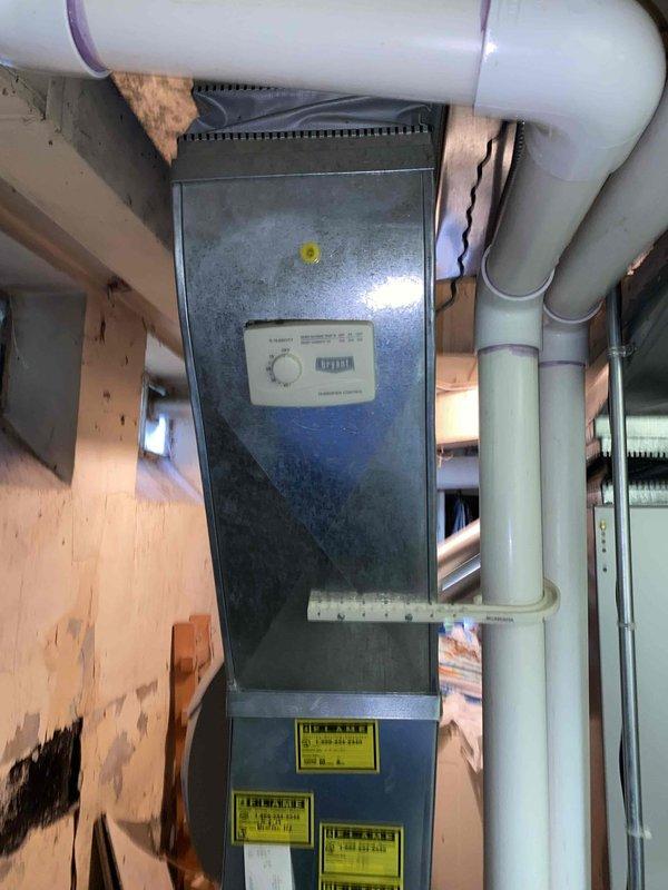 Conducted comprehensive evaluation of 16-year-old air conditioning system located in basement that was experiencing complete cooling failure. Assessed existing HVAC equipment including air handler unit, ductwork configuration, PVC condensate drainage lines, and exhaust venting system. Provided detailed estimate for complete system replacement due to age of equipment and non-operational cooling capacity. Documented current installation setup including metallic exhaust ducting with elbow connections, white PVC drain lines, and existing cabinet-style air handler with control interface. Photographed equipment condition, ductwork connections, surrounding utility room environment, and structural considerations for replacement installation planning.