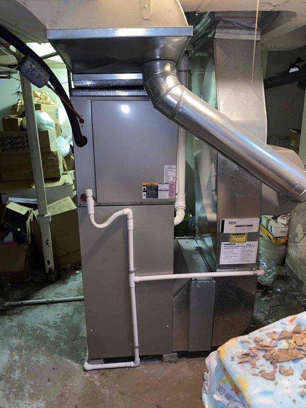 Conducted comprehensive evaluation of 16-year-old air conditioning system located in basement that was experiencing complete cooling failure. Assessed existing HVAC equipment including air handler unit, ductwork configuration, PVC condensate drainage lines, and exhaust venting system. Provided detailed estimate for complete system replacement due to age of equipment and non-operational cooling capacity. Documented current installation setup including metallic exhaust ducting with elbow connections, white PVC drain lines, and existing cabinet-style air handler with control interface. Photographed equipment condition, ductwork connections, surrounding utility room environment, and structural considerations for replacement installation planning.