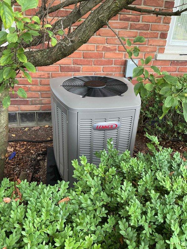 Successfully completed installation of a 2-ton Lennox air conditioning system including outdoor condenser unit and indoor evaporator coil. The outdoor condenser was positioned in the rear yard on a concrete pad against the brick exterior wall with proper clearances maintained for airflow and serviceability. The indoor air handler was installed with appropriate refrigerant line connections, condensate drainage via PVC piping, and electrical connections completed per manufacturer specifications and local code requirements. System was charged, tested, and verified operational with all safety labels and documentation properly affixed.