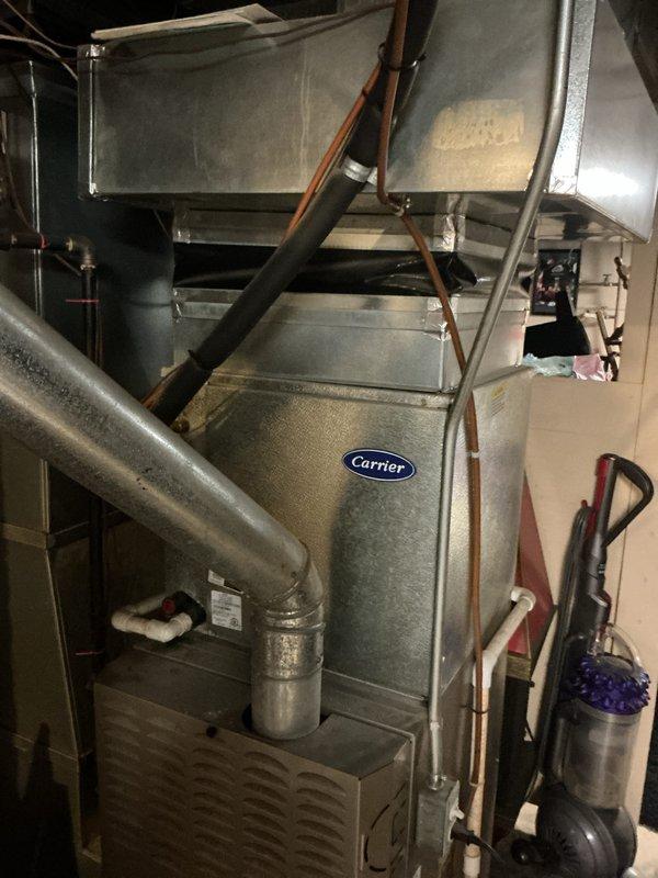 Responded to service call for residential air conditioning system blowing warm air with non-operational condenser fan. Upon inspection of basement-located Carrier HVAC system, evaluated complete forced-air heating and cooling unit including furnace cabinet, air handler, metal ductwork, and refrigerant line configuration. Assessed system components including electrical connections, condensate drain lines, and overall installation integrity to determine equipment viability and provide comprehensive replacement estimate for failed cooling system.