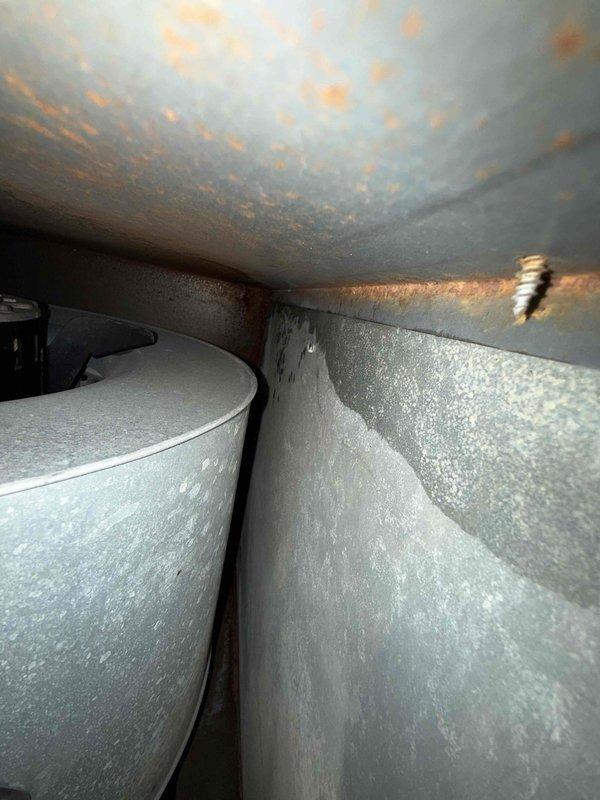Responded to service call for reported pipe leaking at rear of furnace unit. Upon arrival, inspected 11+ year old furnace/AC system located in basement. Performed electrical diagnostics using multimeter to verify system operation and identify potential issues. Inspection revealed extensive rust and corrosion on ceiling surfaces above ductwork, indicating prolonged moisture exposure. Identified copper condensate drain line showing signs of oxidation and corrosion. Water staining visible on metal ductwork surfaces confirmed active or historical moisture infiltration. Documented equipment condition with detailed photographs showing electrical readings, corroded condensate piping, and rust damage to surrounding areas. System requires condensate drain line repair or replacement to resolve leaking issue and prevent further water damage to structure and HVAC components.