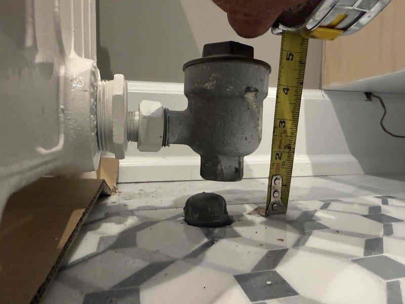 Responded to service call for upstairs bathroom radiator reinstallation assessment. Upon arrival, conducted thorough evaluation of existing radiator system connected to 5-year-old boiler located in basement. Inspected white cast iron multi-column radiator unit and associated plumbing connections, including supply and return piping. Documented current conditions with measurements and photographs showing plumbing fixture assembly, PVC connections, and valve configurations beneath fixture on tiled floor. Assessed radiator mounting requirements, connection points, and compatibility with existing heating system to determine scope of reinstallation work needed.