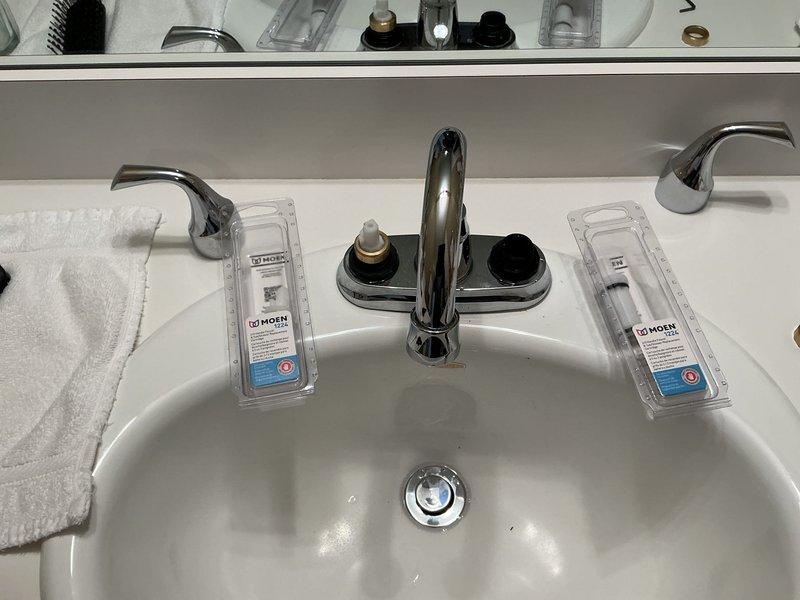 Responded to customer report of leaking bathroom faucet on upper level. Upon inspection, identified worn valve stems on chrome two-handle faucet assembly causing water leak. Removed existing deteriorated valve stems and installed new Moen replacement valve stem cartridges with brass collars. Tested hot and cold water controls for proper operation and verified complete leak elimination. Faucet now functioning properly with no active leaks detected.