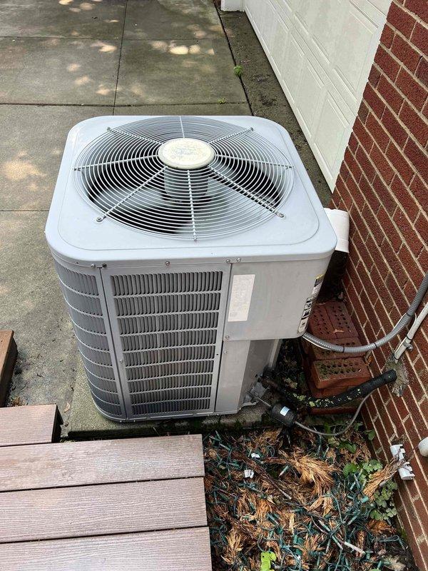 # Summary

Completed comprehensive Gold-level preventive maintenance on a 10-year-old residential air conditioning system with outdoor condenser unit and indoor evaporator coil. No operational issues were reported prior to service, and system performed within normal parameters throughout inspection.

# Work Performed

Conducted thorough inspection of outdoor condenser unit located on concrete pad at side of residence. Removed accumulated debris including pine needles, twigs, and vegetation from around unit base and coil fins to ensure proper airflow. Cleared organic matter and weeds growing near foundation to maintain adequate clearance around equipment.

Inspected condenser coil fins for damage and blockage. Cleaned exterior coil surfaces to restore heat transfer efficiency. Verified fan motor operation and checked fan blade condition for proper balance and secure mounting. Examined refrigerant line insulation and electrical conduit routing along foundation wall for signs of deteriora