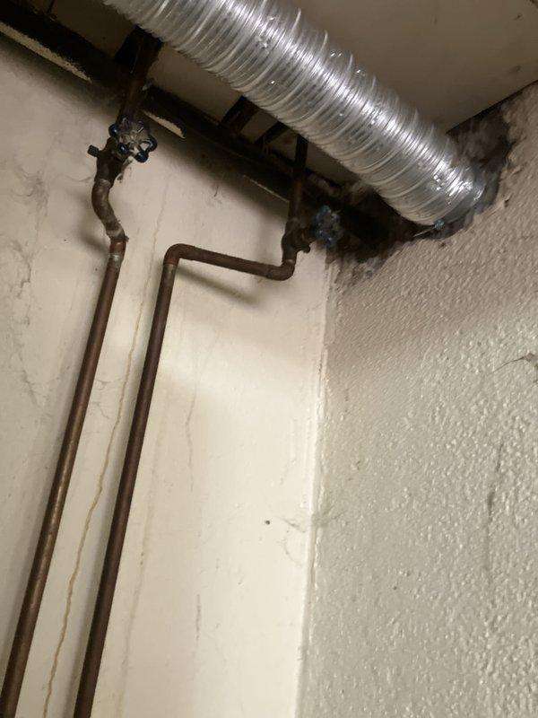 Responded to service call for non-operational air conditioning system. Upon arrival, performed comprehensive assessment of existing HVAC equipment located in basement and backyard. Evaluated aging furnace and air conditioning components, including inspection of ductwork, copper refrigerant lines, and associated piping systems with shut-off valves. Documented current system configuration showing older green metal furnace unit with visible oxidation on copper piping and flexible metallic ductwork. Provided detailed estimate for complete HVAC system replacement to address non-functional outdoor condensing unit and related equipment failure.