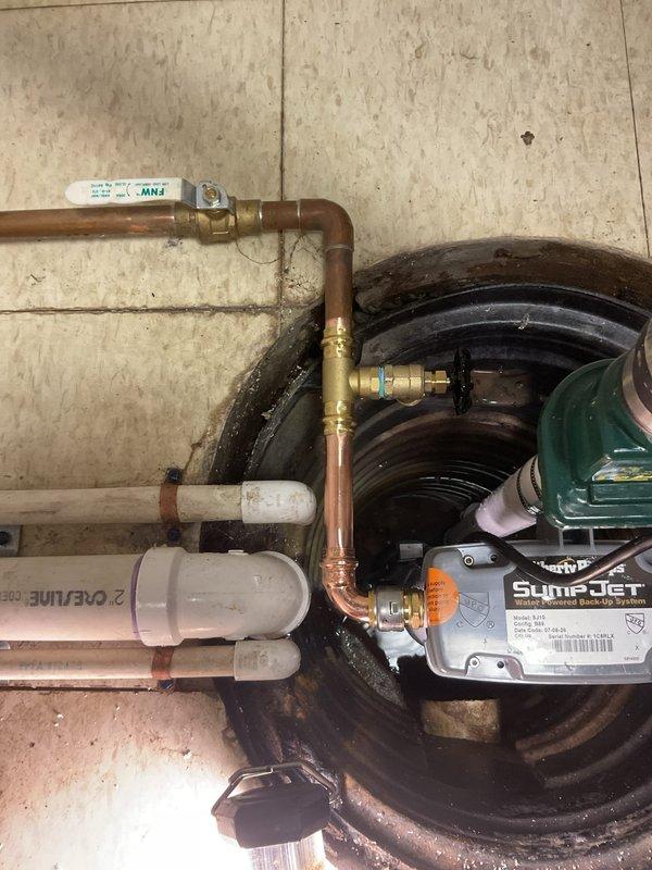 Completed replacement of water-powered backup sump pump system and primary sump pump assembly. Installed new SumpJet water-powered backup unit with proper copper supply line connections utilizing brass ball valves and fittings for system isolation and maintenance access. Configured PVC discharge piping with check valve assembly to prevent backflow and ensure proper drainage operation. Secured all piping components with appropriate mounting hardware and verified system functionality upon completion.
