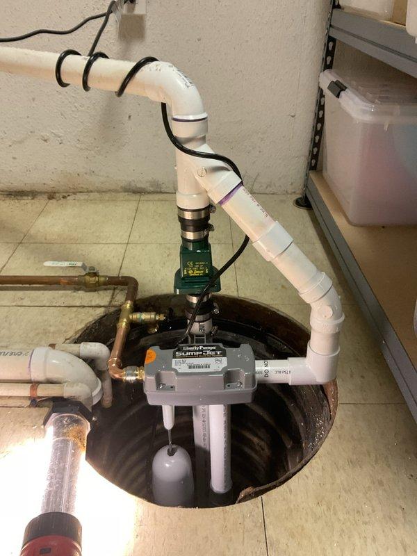 Completed replacement of water-powered backup sump pump system and primary sump pump assembly. Installed new SumpJet water-powered backup unit with proper copper supply line connections utilizing brass ball valves and fittings for system isolation and maintenance access. Configured PVC discharge piping with check valve assembly to prevent backflow and ensure proper drainage operation. Secured all piping components with appropriate mounting hardware and verified system functionality upon completion.