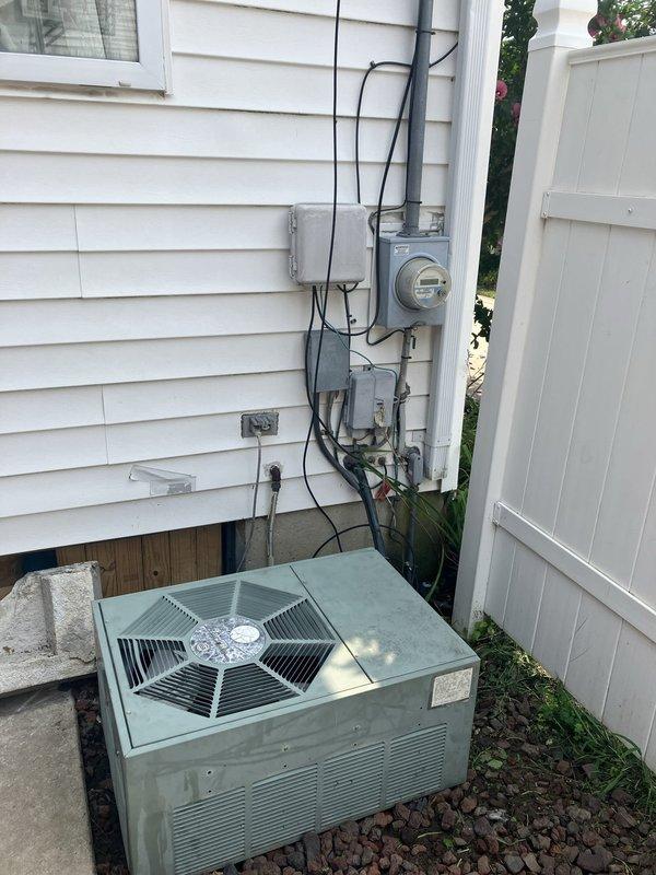Responded to service call for 32-year-old air conditioning system experiencing loud operational noise during startup and shutdown, along with vibration noise during runtime. Upon arrival, inspected 1994-era condensing unit located in side yard between structures, mounted on concrete pad with lava rock landscaping. Unit was still providing cooling but exhibited signs of significant age-related wear consistent with equipment nearing end of service life. Documented existing installation including electrical service connections, meter configuration, and current equipment positioning. Performed comprehensive evaluation of condensing unit cabinet, fan assembly with protective guard, compressor operation, and mounting stability. Assessed noise sources related to aging mechanical components, worn motor bearings, and potential compressor issues typical of three-decade-old equipment. Photographed current installation showing unit placement, electrical infrastructure, surrounding clearances, and 