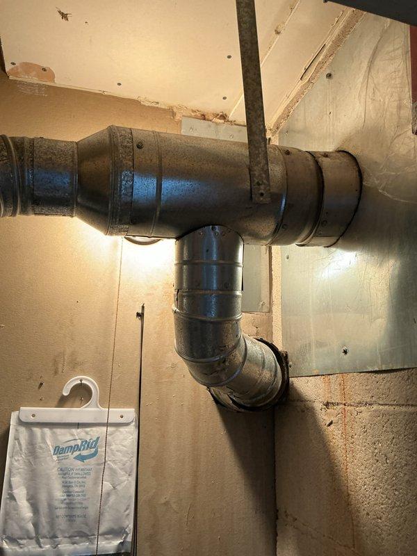 Conducted comprehensive assessment of existing 20-year-old furnace system located in utility closet for potential central air conditioning integration. Evaluated current HVAC infrastructure including furnace unit, existing ductwork configuration, and available space for AC component installation. Documented equipment specifications, duct routing through basement area, and structural considerations necessary for complete system upgrade. Photographed furnace unit with visible manufacturer labeling and existing metallic supply duct system to support estimate preparation for full HVAC system installation.