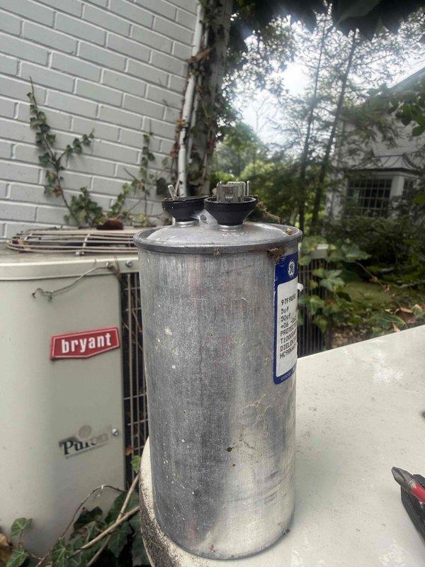 Responded to service call for one of two AC units not operating at residential property. Located Bryant outdoor condenser unit with failed capacitor. Unit showed signs of age consistent with 10+ year old equipment, with visible weathering and oxidation on components. Diagnosed faulty dual run capacitor preventing compressor and condenser fan operation. Removed failed capacitor and installed new replacement unit with proper microfarad ratings. Verified electrical connections secure at terminals. Restored power to system and confirmed compressor startup and condenser fan rotation. Tested system operation through complete cooling cycle. Unit now cooling properly. Advised homeowner that air handler located in attic was functioning correctly and issue was isolated to outdoor unit capacitor failure. Left work area clean and operational.