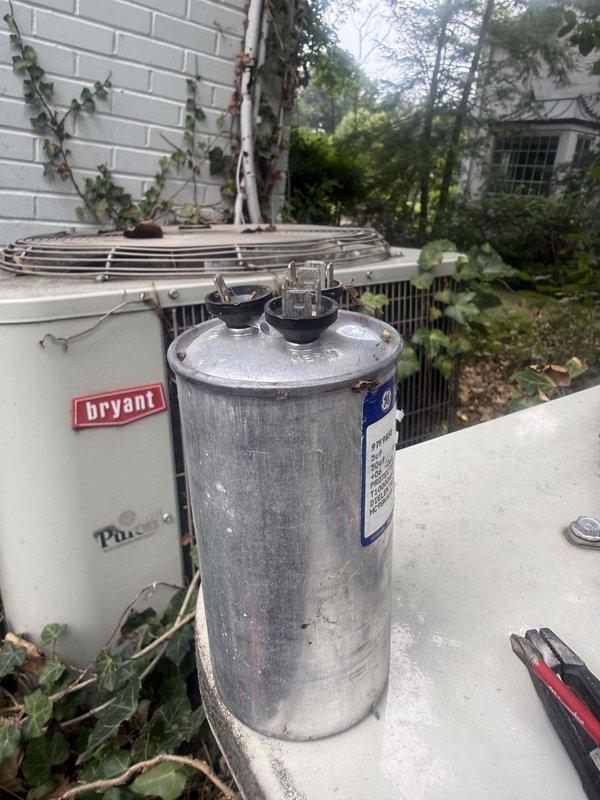 Responded to service call for one of two AC units not operating at residential property. Located Bryant outdoor condenser unit with failed capacitor. Unit showed signs of age consistent with 10+ year old equipment, with visible weathering and oxidation on components. Diagnosed faulty dual run capacitor preventing compressor and condenser fan operation. Removed failed capacitor and installed new replacement unit with proper microfarad ratings. Verified electrical connections secure at terminals. Restored power to system and confirmed compressor startup and condenser fan rotation. Tested system operation through complete cooling cycle. Unit now cooling properly. Advised homeowner that air handler located in attic was functioning correctly and issue was isolated to outdoor unit capacitor failure. Left work area clean and operational.