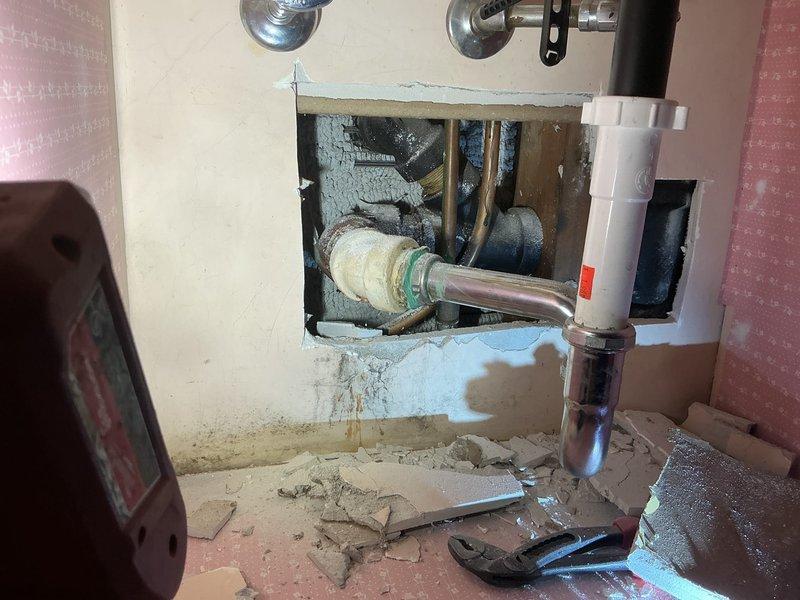 Responded to intermittent drain pipe leak at joint in 80-year-old residential property. Opened interior wall to access deteriorated plumbing system, revealing rusted pipes with visible water damage and corrosion. Located leak isolated to single joint connection in aged copper piping assembly with brass fittings. Assessed structural cavity showing evidence of long-term moisture intrusion and compromised pipe integrity. Documented existing conditions including corroded fixtures, water staining, and deteriorated wall materials surrounding plumbing infrastructure. Work performed during requested late-afternoon service window to accommodate scheduling preferences.