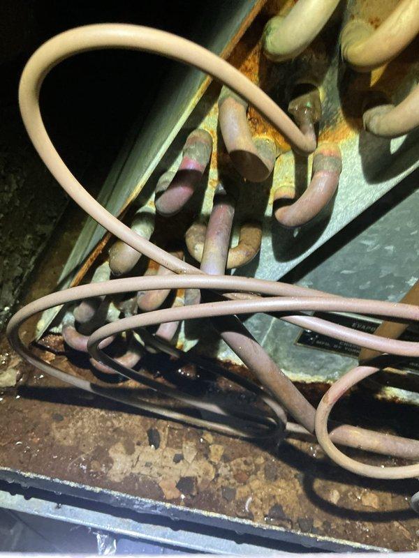 Responded to service call for reported water leak near forced air furnace located in basement. Upon inspection, discovered significant corrosion and rust on condensate drain components and associated piping connections. Evidence of prolonged moisture exposure observed on metal fittings, brackets, and drain pan assembly. Photographed deteriorated conditions including corroded gauge assembly and compromised drainage system components. Identified source of leak as failed condensate management system with blocked or damaged drain lines. Recommended immediate repair or replacement of affected components to prevent further water damage and ensure proper system operation.