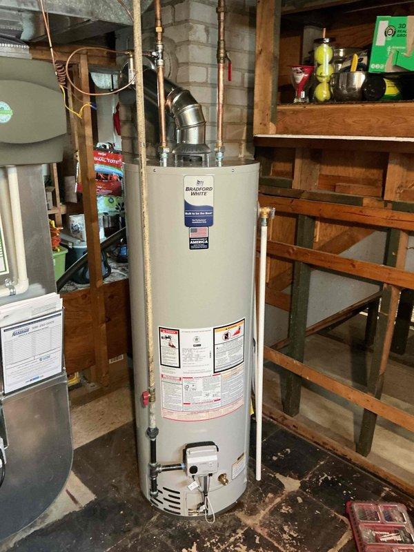Replaced 40-gallon Bradford White gas water heater in basement due to tank leaking from the bottom. The 8-year-old unit was replaced under warranty with gas connection kit and copper piping kit installed with the new tank. All connections, venting, and system operations were verified upon completion.