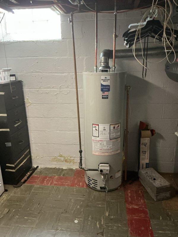 Completed installation of 40-gallon tanked water heater in basement utility room. Unit was positioned on concrete floor with proper clearances, copper supply lines connected to overhead plumbing, and venting configured for safe exhaust operation. All connections were secured and tested to ensure proper water flow and system functionality.