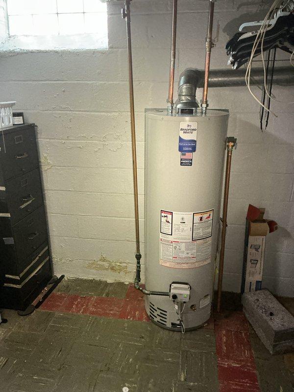 Completed installation of 40-gallon tanked water heater in basement utility room. Unit was positioned on concrete floor with proper clearances, copper supply lines connected to overhead plumbing, and venting configured for safe exhaust operation. All connections were secured and tested to ensure proper water flow and system functionality.