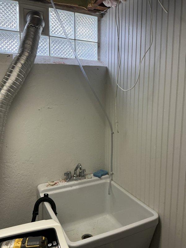 Completed installation of 2.5 ton air conditioning system with evaporator coil in right side yard location. Obtained mechanical, electrical, and AC permits, performed system reconnection, and documented installation with photos of utility room area showing workspace conditions. Noted existing humidifier drainage concern for follow-up attention.