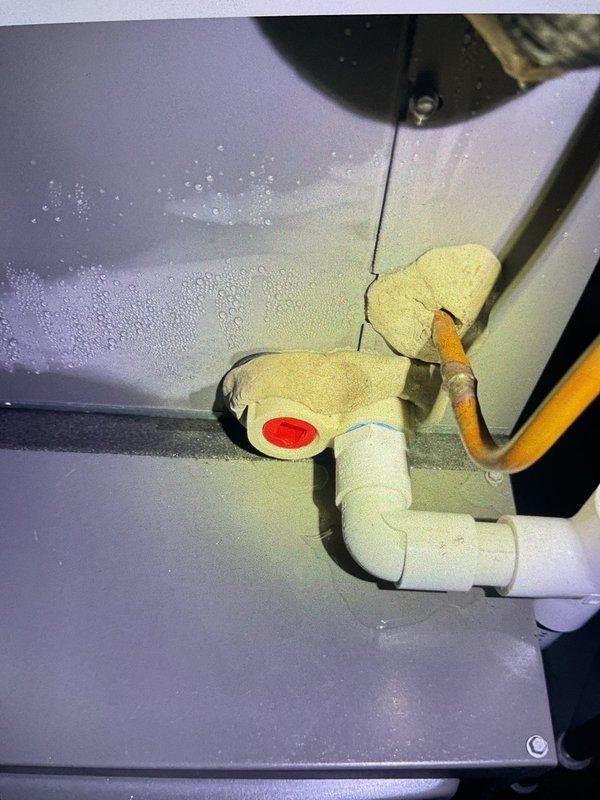 Responded to commercial AC unit in basement that had been offline since previous evening due to refrigerant line freezing and excessive condensation on exterior surfaces. Upon inspection, discovered significant frost buildup and moisture accumulation on evaporator coil and surrounding metal surfaces, indicating restricted airflow or low refrigerant charge causing suction line to ice over. Documented heavy condensation on equipment cabinet and copper refrigeration lines with deteriorated insulation. System exhibited classic symptoms of freeze-up condition with visible ice formation preventing proper heat exchange. Photographed affected components showing condensation patterns on painted metal surfaces and compromised pipe insulation on both liquid and suction lines.