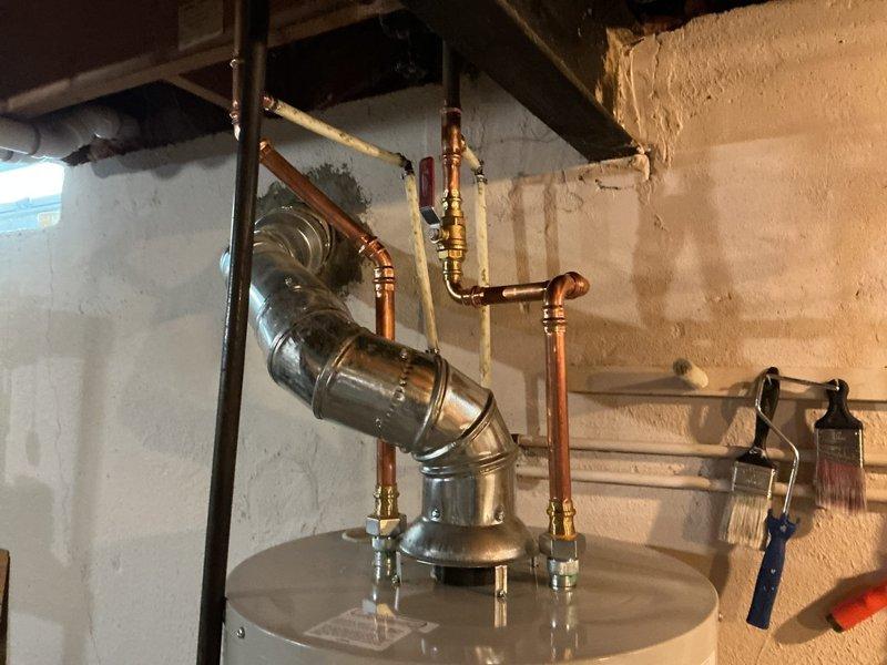 # Plumbing Install - Tanked Water Heater

Successfully installed a 40-gallon standard residential water heater in basement utility area. Removed existing unit and positioned new water heater on concrete floor in compliance with local plumbing codes. Connected copper supply and discharge lines to unit using brass fittings and shut-off valves for proper water flow control. Installed metallic vent pipe with elbow joint to ensure safe exhaust of combustion gases, routing ductwork upward through ceiling joists. Verified all connections for leaks, tested temperature and pressure relief valve operation, and confirmed proper venting. System was pressurized, tested for functionality, and left in full operational condition.