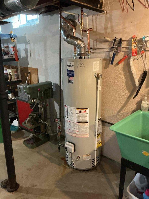 # Plumbing Install - Tanked Water Heater

Successfully installed a 40-gallon standard residential water heater in basement utility area. Removed existing unit and positioned new water heater on concrete floor in compliance with local plumbing codes. Connected copper supply and discharge lines to unit using brass fittings and shut-off valves for proper water flow control. Installed metallic vent pipe with elbow joint to ensure safe exhaust of combustion gases, routing ductwork upward through ceiling joists. Verified all connections for leaks, tested temperature and pressure relief valve operation, and confirmed proper venting. System was pressurized, tested for functionality, and left in full operational condition.