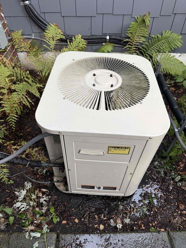 Completed comprehensive Gold AC inspection on 25-30 year old outdoor heat pump unit located on exterior concrete pad with basement air handler. Performed full system diagnostic including electrical testing with multimeter, measuring voltage and amperage at capacitor and electrical connections to verify proper operation of all components. Inspected outdoor unit condition, refrigerant lines, conduit routing, and surrounding clearances with adequate vegetation spacing. All electrical readings within acceptable parameters, unit operating as designed with no immediate service needs identified. Documented system condition with photos for maintenance records.