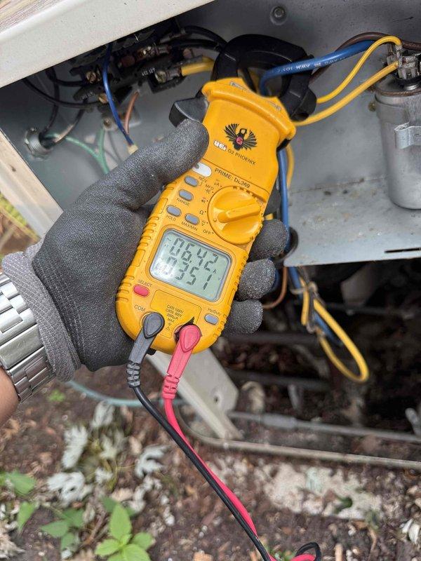 Completed comprehensive Gold AC inspection on 25-30 year old outdoor heat pump unit located on exterior concrete pad with basement air handler. Performed full system diagnostic including electrical testing with multimeter, measuring voltage and amperage at capacitor and electrical connections to verify proper operation of all components. Inspected outdoor unit condition, refrigerant lines, conduit routing, and surrounding clearances with adequate vegetation spacing. All electrical readings within acceptable parameters, unit operating as designed with no immediate service needs identified. Documented system condition with photos for maintenance records.