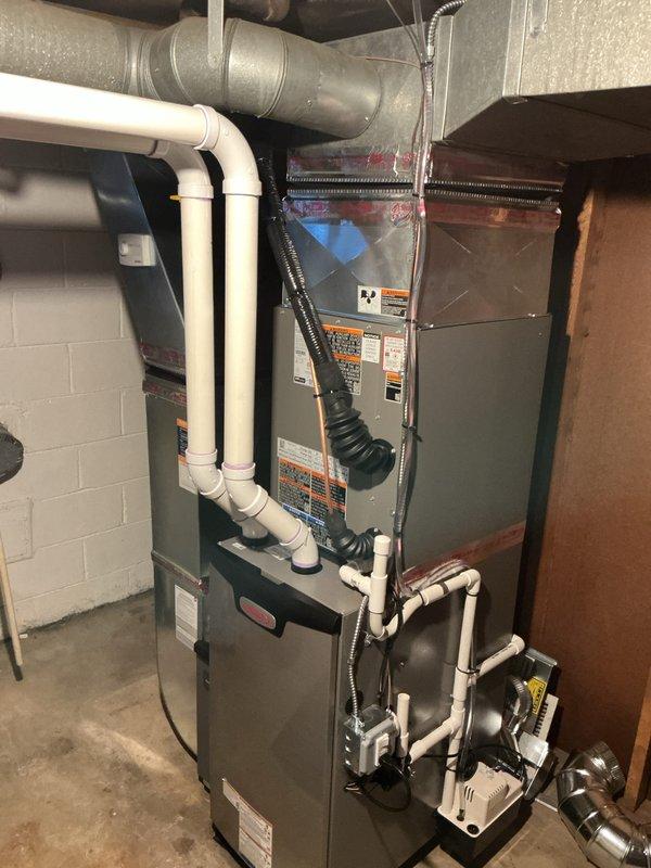 Completed full HVAC system replacement in residential basement mechanical room. Installed new 70,000 BTU furnace with matching 2.5 ton air conditioning system, programmable thermostat, and humidifier. Configured proper venting using white PVC piping with appropriate elbow connections for condensate drainage. Installed condensate pump to manage system drainage. Connected gray sheet metal ductwork to distribution system and established proper airflow pathways using black flexible duct connections. Reconnected all electrical and mechanical components to existing infrastructure. Performed system flush and secured all required mechanical and electrical permits prior to installation. Verified AHRI certification matching (certificate #215663829) for optimal system efficiency and utility rebate qualification. Conducted final system testing to ensure proper furnace ignition, air conditioning cooling cycle, humidifier operation, and thermostat functionality. All equipment installed per manufactu