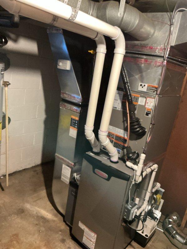 Completed full HVAC system replacement in residential basement mechanical room. Installed new 70,000 BTU furnace with matching 2.5 ton air conditioning system, programmable thermostat, and humidifier. Configured proper venting using white PVC piping with appropriate elbow connections for condensate drainage. Installed condensate pump to manage system drainage. Connected gray sheet metal ductwork to distribution system and established proper airflow pathways using black flexible duct connections. Reconnected all electrical and mechanical components to existing infrastructure. Performed system flush and secured all required mechanical and electrical permits prior to installation. Verified AHRI certification matching (certificate #215663829) for optimal system efficiency and utility rebate qualification. Conducted final system testing to ensure proper furnace ignition, air conditioning cooling cycle, humidifier operation, and thermostat functionality. All equipment installed per manufactu