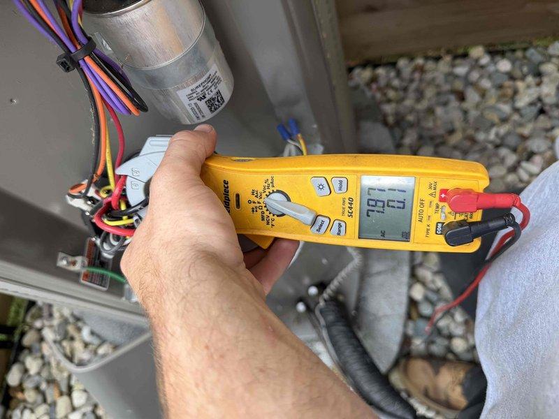 Completed comprehensive Gold AC inspection on residential property with two 2-year-old air conditioning systems. Performed thorough evaluation of outdoor condensing unit located on concrete pad with proper drainage and clearance. Conducted electrical diagnostics using digital multimeter to verify proper voltage, amperage, and capacitor function across all electrical components. Inspected wiring connections, terminals, and capacitor for signs of wear or degradation. Evaluated indoor air handler/coil equipment located in basement boiler room. Verified both units are operating within manufacturer specifications with no immediate service needs identified. All safety labels and equipment markings present and legible. System showing normal operation for equipment age with proper maintenance evident from clean installation and surrounding area. Documented equipment condition through photographic records for service history.