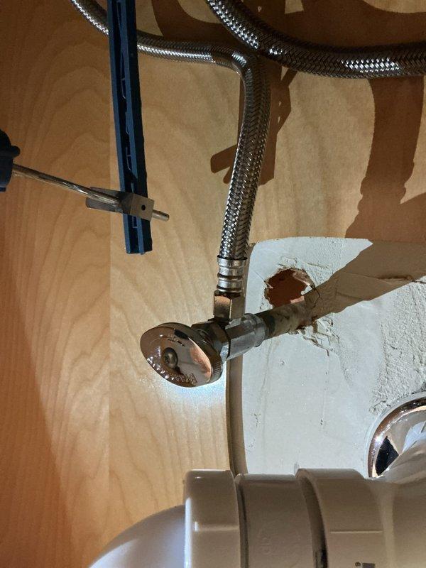 Completed drain line repair beneath kitchen sink. Removed and replaced deteriorated P-trap assembly with new white PVC piping and fittings, ensuring proper trap configuration for effective drainage and sewer gas prevention. Installed new drain tailpiece with threaded connection to accommodate sink basket strainer. Verified flexible braided water supply line connections to shut-off valve and faucet supply shank, confirming secure fittings without leaks. Tested entire drain assembly for proper flow and checked all connections under pressure. System operating correctly with no leaks detected at drain connections or supply line fittings.