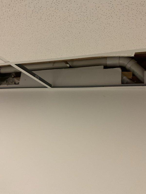 Performed video camera inspection of plumbing drain lines accessible through ceiling plenum space above bathroom facilities. Removed acoustic ceiling tiles to access and inspect gray PVC drainage piping system, including horizontal runs and elbow connections. Documented existing pipe configuration and condition with photographic evidence. Inspected bathroom fixture connections, including toilet drain line, to assess drainage system integrity and identify any potential blockages or concerns within the visible plumbing infrastructure.